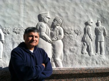 A picture of the sculptor eliseo with one of his reliefs