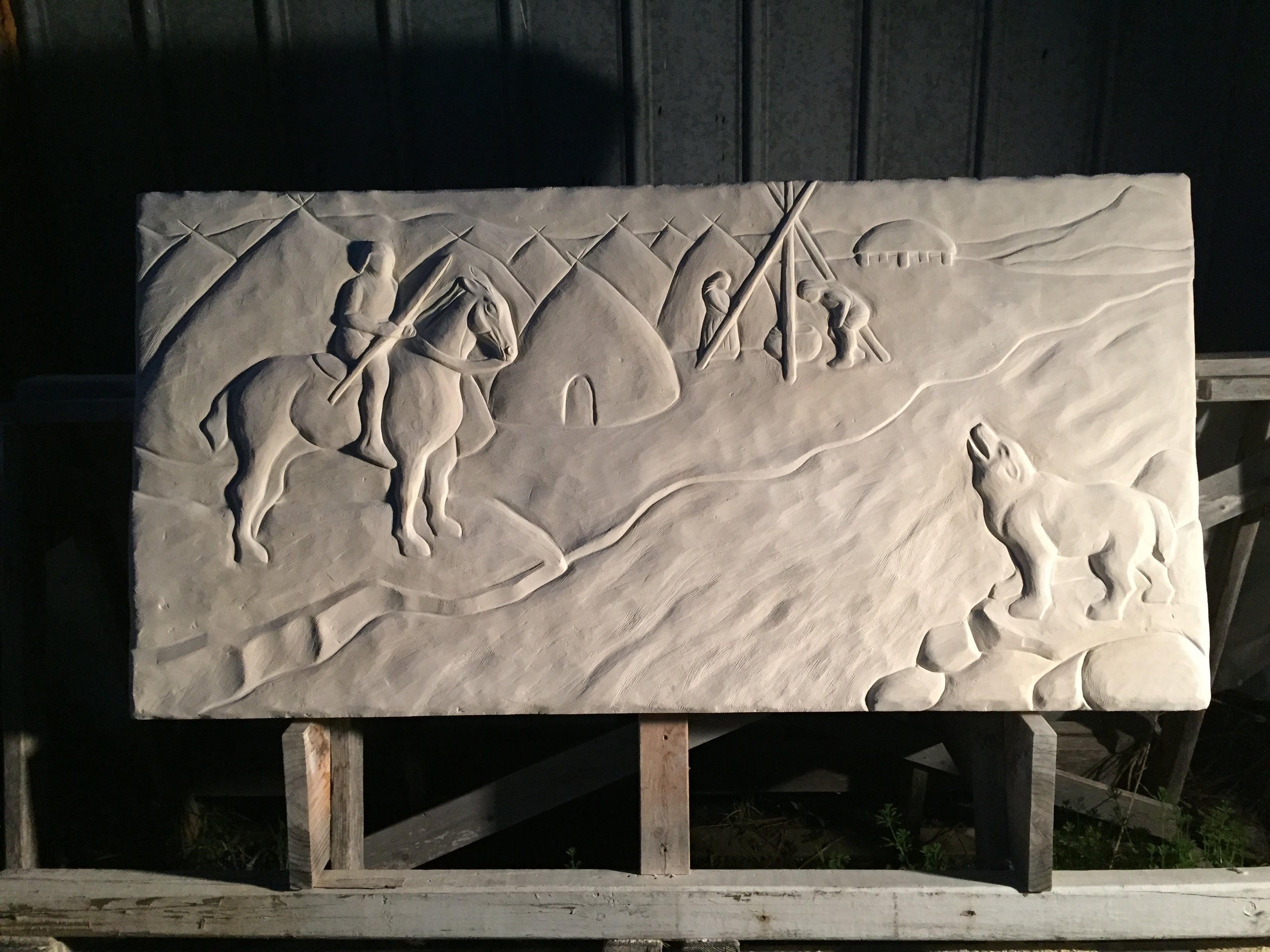 Long Cove Relief with images of Native Americans overlooking a river and a wolf on the other side carved in limestone
